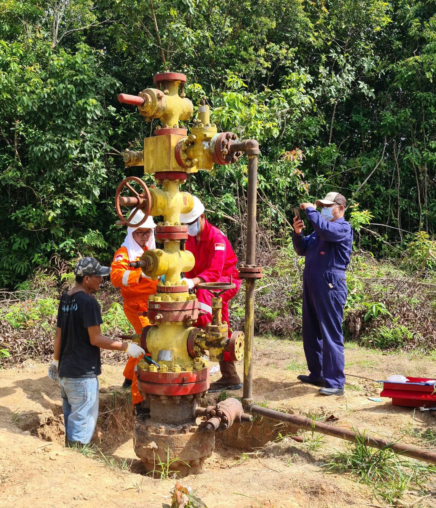 Technicians inspecting a surface wellhead